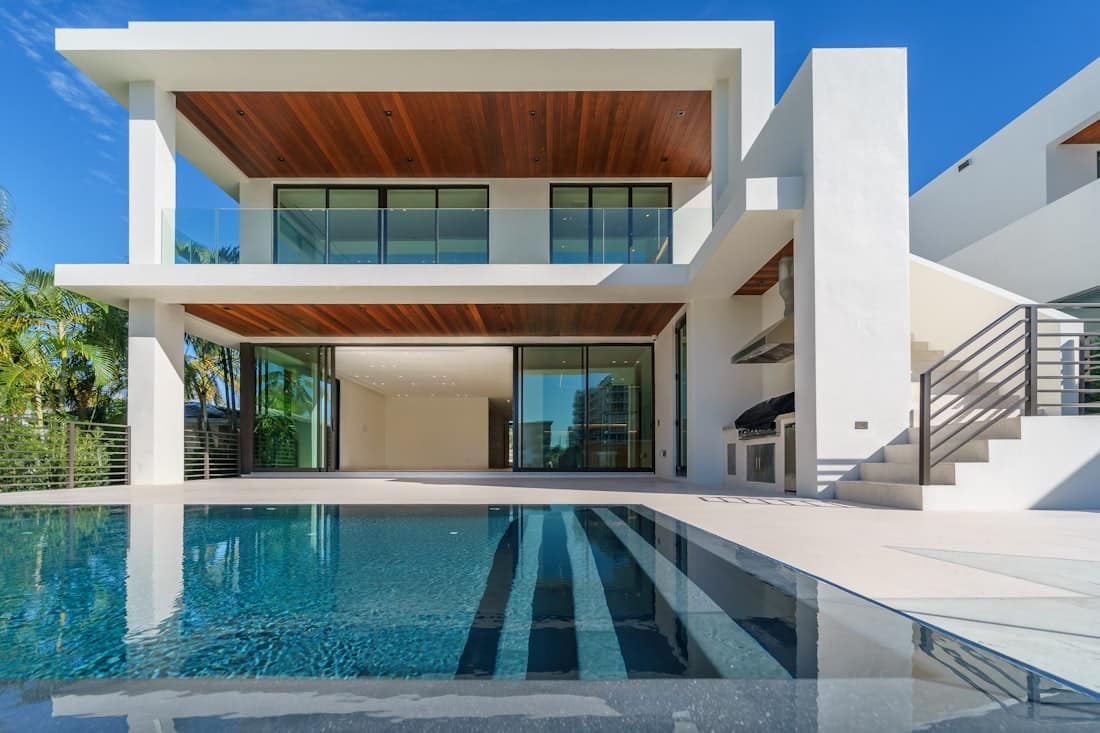 Modern geometric pool with dark tile beside a contemporary white home